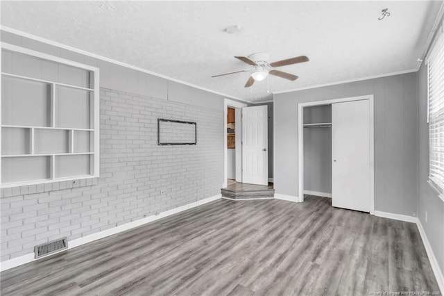 5409 S Sumac Cir, Fayetteville, NC 28304 - unfurnished bedroom with ornamental molding, wood finished floors, brick wall, a closet, and a textured ceiling