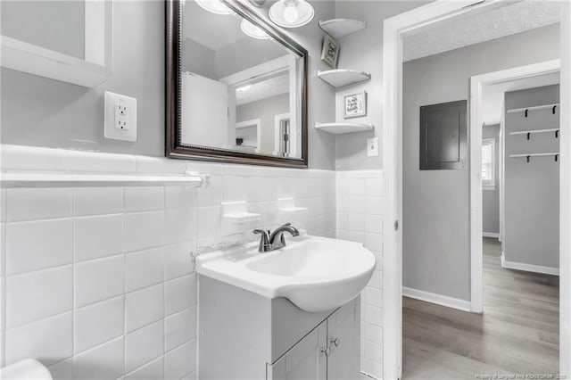 5409 S Sumac Cir, Fayetteville, NC 28304 - bathroom featuring wood finished floors, vanity, tile walls, wainscoting, and electric panel