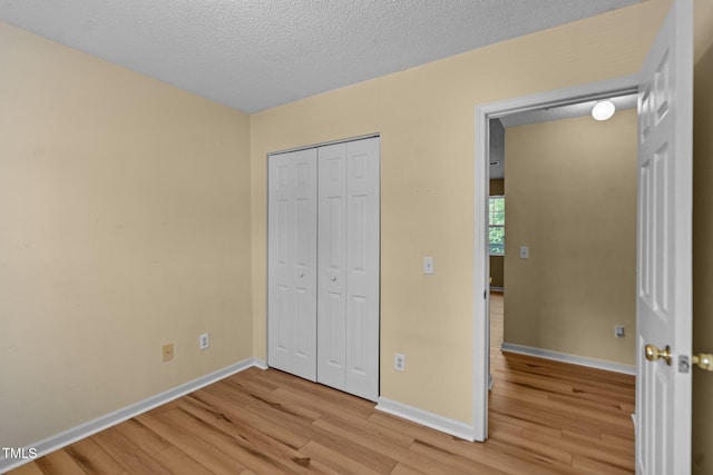 5134 Greenville Loop Rd Apt D, Wilmington, NC 28409 - unfurnished bedroom with light wood-type flooring, baseboards, a closet, and a textured ceiling