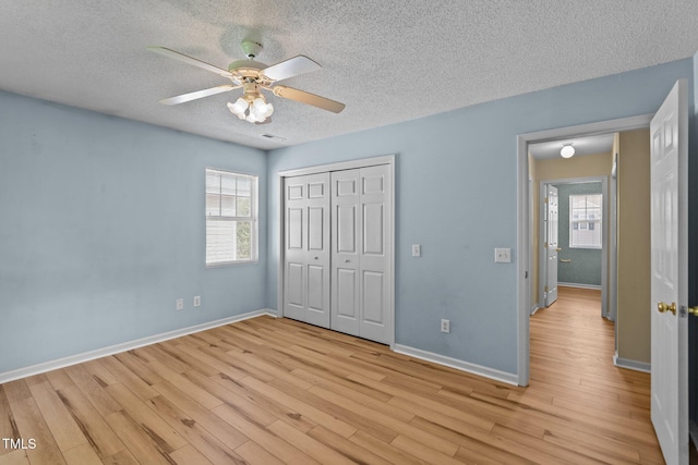 5134 Greenville Loop Rd Apt D, Wilmington, NC 28409 - unfurnished bedroom featuring light wood finished floors, a textured ceiling, multiple windows, a closet, and baseboards