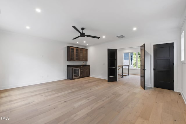 2805 Van Dyke Ave, Raleigh, NC 27607 - unfurnished living room featuring beverage cooler, ornamental molding, baseboards, ceiling fan, and light wood-style floors
