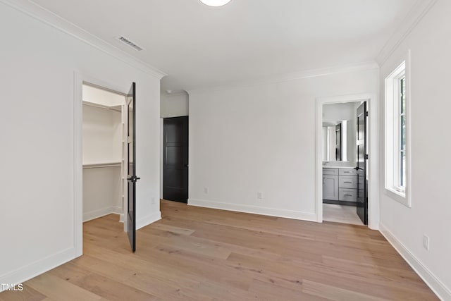 2805 Van Dyke Ave, Raleigh, NC 27607 - unfurnished bedroom with a spacious closet, multiple windows, light wood-type flooring, crown molding, and baseboards