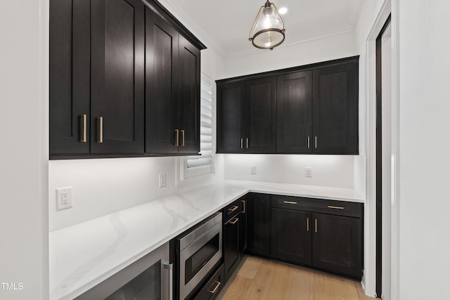 2805 Van Dyke Ave, Raleigh, NC 27607 - kitchen with stainless steel microwave, light stone counters, light wood-style flooring, dark cabinets, and ornamental molding