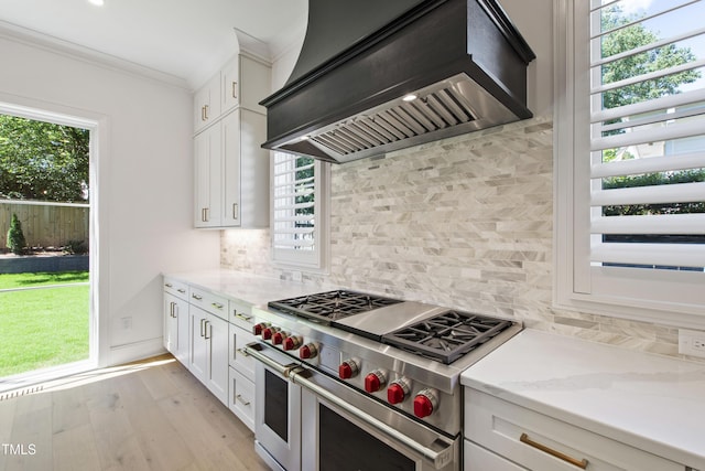 2805 Van Dyke Ave, Raleigh, NC 27607 - kitchen featuring double oven range, wall chimney exhaust hood, ornamental molding, light stone counters, and white cabinetry