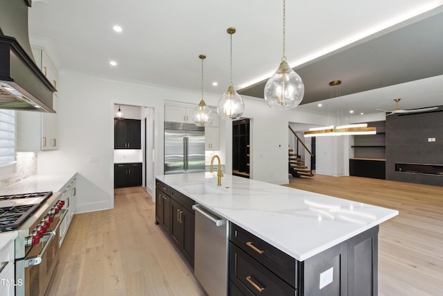2805 Van Dyke Ave, Raleigh, NC 27607 - kitchen with high quality appliances, a sink, wall chimney exhaust hood, light wood finished floors, and ornamental molding