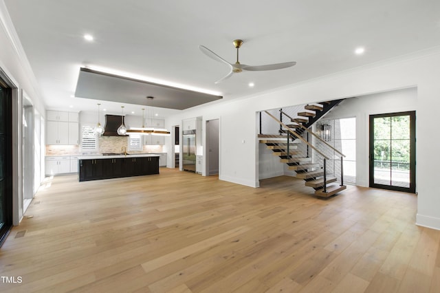 2805 Van Dyke Ave, Raleigh, NC 27607 - unfurnished living room featuring stairs, a ceiling fan, baseboards, a sink, and crown molding