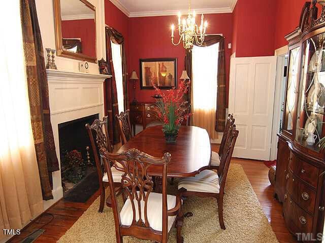100 Lager Ln, Garner, NC 27529 - dining area with a chandelier, wood finished floors, a fireplace, and ornamental molding