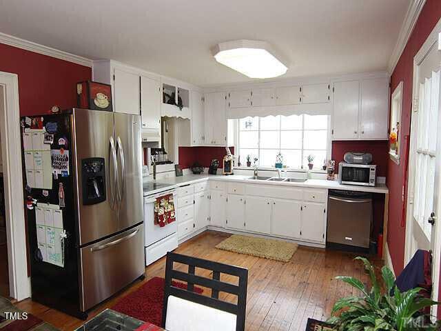 100 Lager Ln, Garner, NC 27529 - kitchen featuring appliances with stainless steel finishes, crown molding, light countertops, dark wood finished floors, and white cabinetry