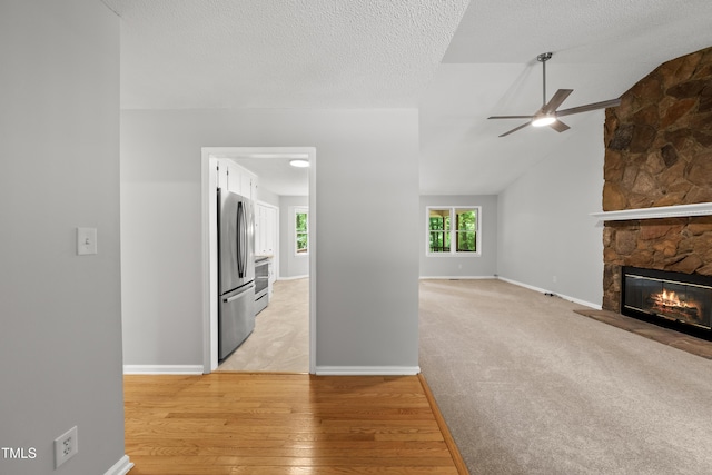 6009 Shadow Moss Cir, Raleigh, NC 27603 - unfurnished living room featuring ceiling fan, a fireplace, light wood-style flooring, baseboards, and a textured ceiling