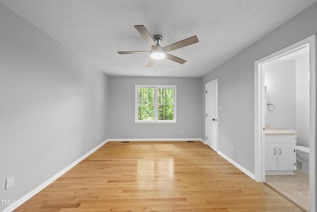 6009 Shadow Moss Cir, Raleigh, NC 27603 - unfurnished bedroom with light wood-style flooring, a textured ceiling, baseboards, and connected bathroom