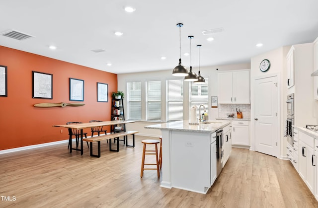 6928 Leesville Rd, Raleigh, NC 27613 - kitchen featuring a kitchen island, light wood finished floors, recessed lighting, white cabinets, and a kitchen bar