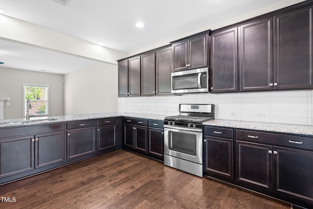 33 E Ravano Dr, Clayton, NC 27527 - kitchen with stainless steel appliances, light stone countertops, dark wood finished floors, a sink, and backsplash