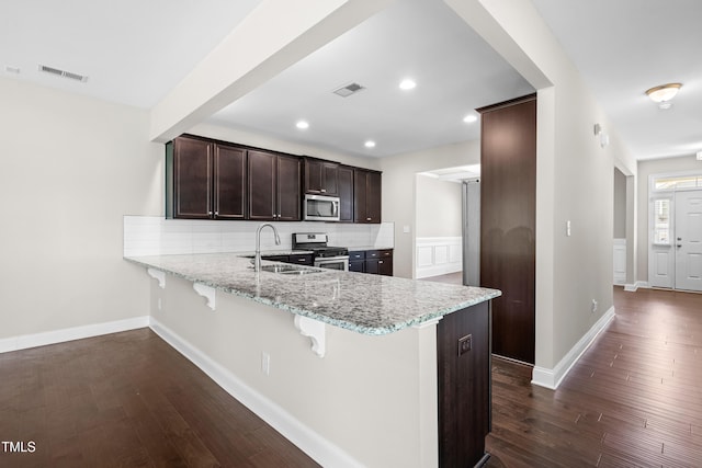33 E Ravano Dr, Clayton, NC 27527 - kitchen with stainless steel appliances, a sink, dark wood-style flooring, light stone countertops, and a breakfast bar area