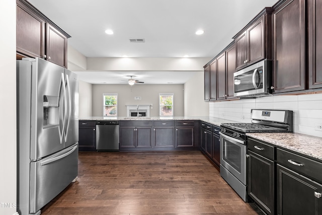33 E Ravano Dr, Clayton, NC 27527 - kitchen featuring appliances with stainless steel finishes, ceiling fan, light stone countertops, dark wood finished floors, and dark brown cabinetry