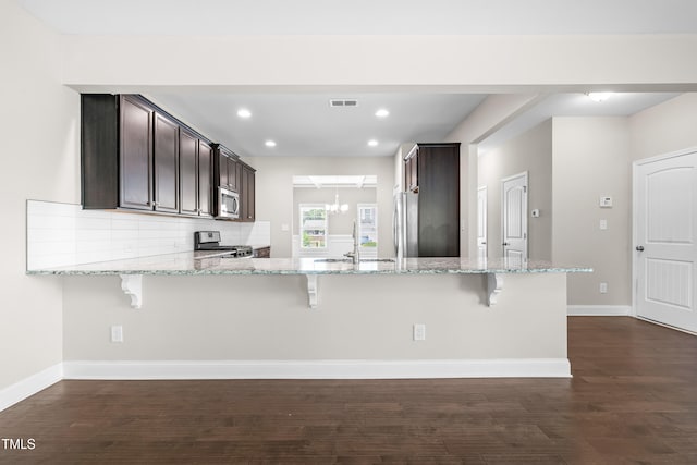 33 E Ravano Dr, Clayton, NC 27527 - kitchen featuring appliances with stainless steel finishes, dark wood-style flooring, dark brown cabinets, a kitchen breakfast bar, and recessed lighting
