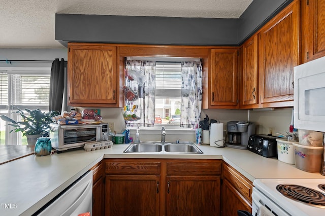 113 W Victoria Ct Unit C, Greenville, NC 27834 - kitchen featuring a sink, light countertops, white appliances, a textured ceiling, and brown cabinets