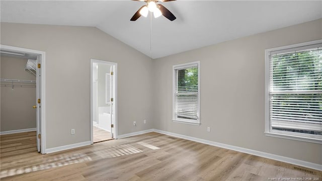 21 Dinghy Dr, Sanford, NC 27332 - unfurnished bedroom featuring a walk in closet, light wood-style flooring, vaulted ceiling, baseboards, and a closet