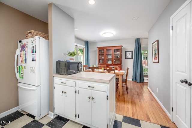 903 W Maynard Ave, Durham, NC 27704 - kitchen featuring freestanding refrigerator, black microwave, light countertops, white cabinets, and baseboards