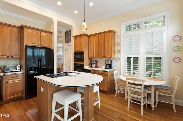 3928 Bentley Bridge Rd, Raleigh, NC 27612 - kitchen with black appliances, crown molding, a kitchen island, wood finished floors, and a kitchen bar