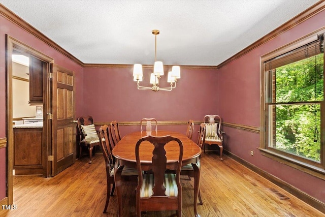 5125 Penny Rd, Raleigh, NC 27606 - dining space with light wood-style floors, crown molding, and a chandelier