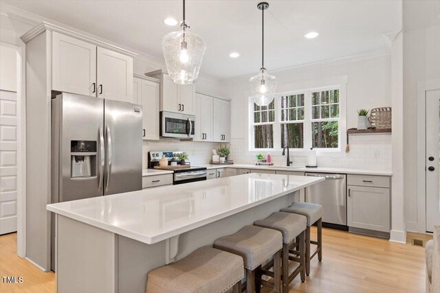 210 Sorrel Dr, Franklinton, NC 27525 - kitchen featuring appliances with stainless steel finishes, light wood-style flooring, ornamental molding, decorative backsplash, and a breakfast bar
