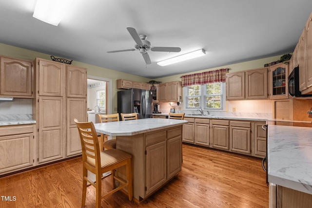 2127 Somers Ave, Burlington, NC 27215 - kitchen featuring black refrigerator with ice dispenser, a sink, a kitchen bar, a center island, and decorative backsplash
