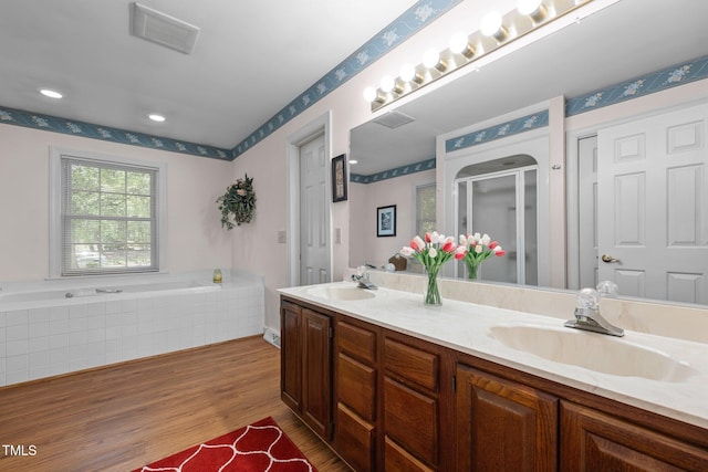 2127 Somers Ave, Burlington, NC 27215 - bathroom with double vanity, a stall shower, wood finished floors, a bath, and recessed lighting