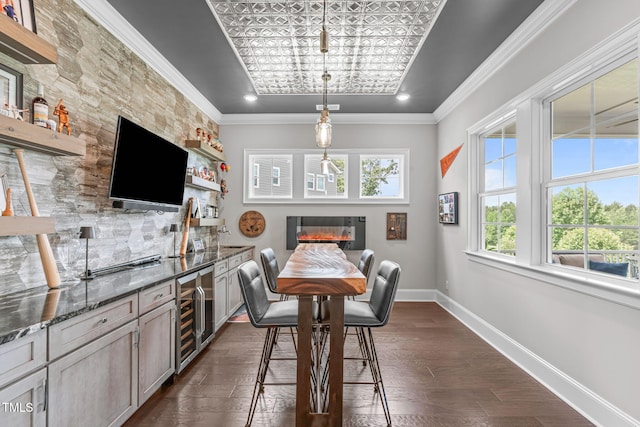200 Baskerville Ct, Holly Springs, NC 27540 - dining area featuring wine cooler, a glass covered fireplace, dark wood-style floors, bar with sink, and ornamental molding