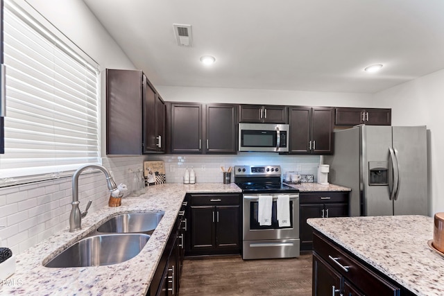 218 Mason Rd, Durham, NC 27712 - kitchen featuring appliances with stainless steel finishes, a sink, dark wood-style flooring, tasteful backsplash, and light stone countertops