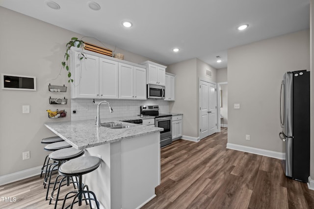 412 Carr Store Rd, Cedar Grove, NC 27231 - kitchen with stainless steel appliances, a sink, a kitchen breakfast bar, white cabinets, and a peninsula
