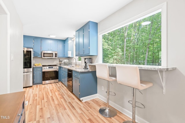 114 Bonaparte Dr, Hillsborough, NC 27278 - kitchen featuring appliances with stainless steel finishes, blue cabinetry, a sink, light wood-style floors, and baseboards