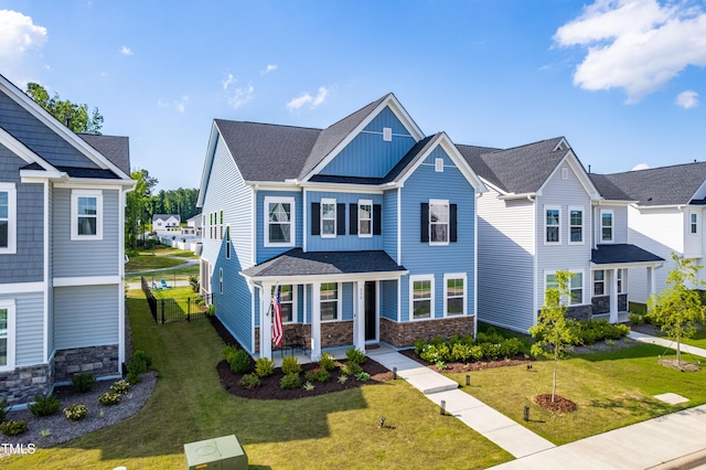 279 Edge Of Auburn Blvd, Raleigh, NC 27610 - view of front of house featuring stone siding, a front yard, a porch, board and batten siding, and a shingled roof