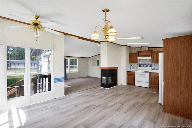 6131 Twiggs Ct, Hope Mills, NC 28348 - kitchen with white appliances, under cabinet range hood, brown cabinets, vaulted ceiling, and light countertops