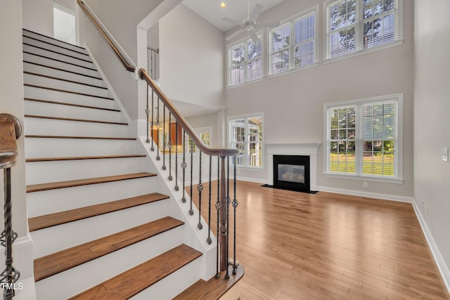 805 Alden Bridge Dr, Cary, NC 27519 - stairway with a ceiling fan, a towering ceiling, wood finished floors, a fireplace with flush hearth, and baseboards
