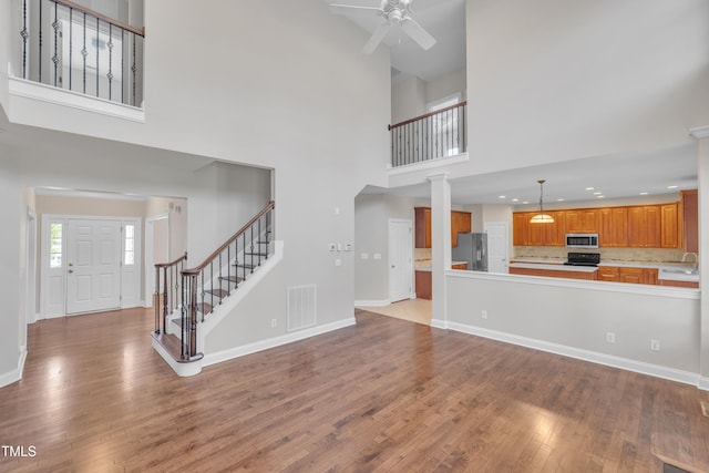 805 Alden Bridge Dr, Cary, NC 27519 - unfurnished living room with a high ceiling, ceiling fan, wood finished floors, stairs, and baseboards