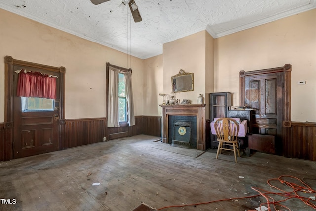 903 Nicholas St, Henderson, NC 27536 - living area featuring a wainscoted wall, ceiling fan, wooden walls, ornamental molding, and a fireplace with flush hearth