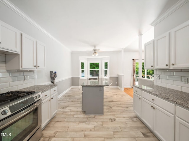 8312 Bellingham Cir, Raleigh, NC 27615 - kitchen with stainless steel range with gas stovetop, a ceiling fan, baseboards, plenty of natural light, and ornamental molding