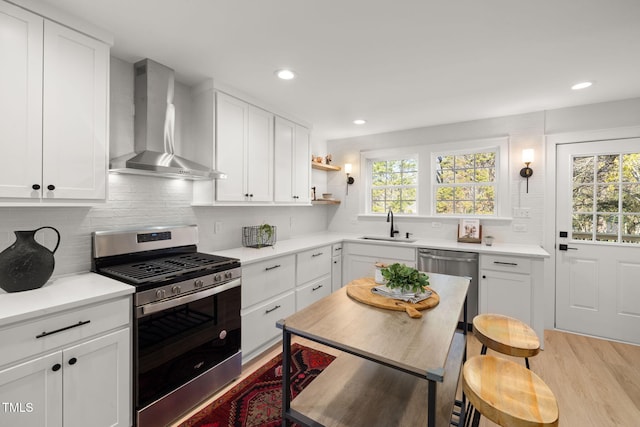 18 W Academy St, Wendell, NC 27591 - kitchen with appliances with stainless steel finishes, wall chimney range hood, light wood finished floors, white cabinetry, and recessed lighting