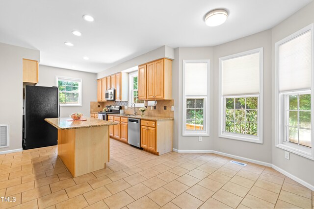 203 Worsham Dr, Chapel Hill, NC 27516 - kitchen with stainless steel appliances, a sink, backsplash, light tile patterned floors, and a center island