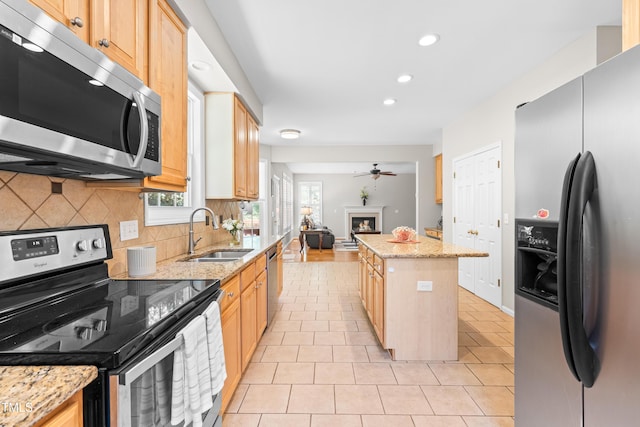 203 Worsham Dr, Chapel Hill, NC 27516 - kitchen featuring appliances with stainless steel finishes, a sink, a glass covered fireplace, tasteful backsplash, and recessed lighting