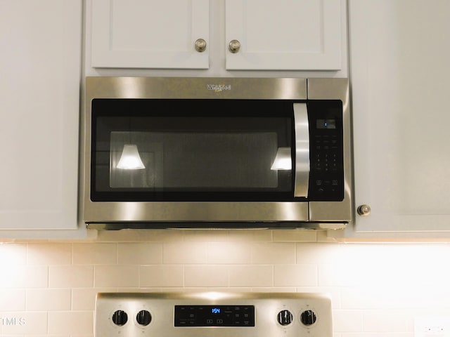 1311 Arena Ln, Fuquay Varina, NC 27526 - kitchen view of stainless steel microwave, white cabinetry, tasteful backsplash, and stove