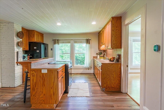 5625 Church Rd, Graham, NC 27253 - kitchen featuring freestanding refrigerator, electric range, a sink, a breakfast bar, and brown cabinetry