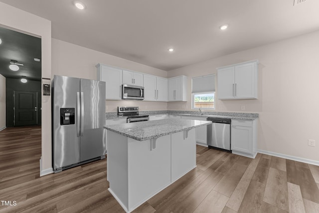 1401 Justice Union Ct, Raleigh, NC 27604 - kitchen with appliances with stainless steel finishes, white cabinets, a center island, dark wood-style flooring, and light stone counters