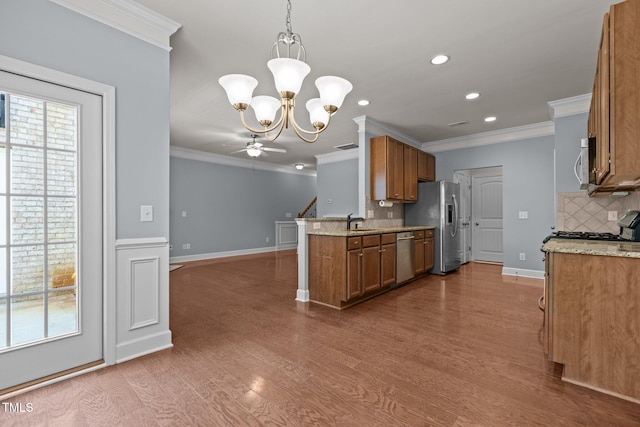 2082 Weston Green Loop, Cary, NC 27513 - kitchen featuring stainless steel appliances, a sink, brown cabinetry, plenty of natural light, and crown molding