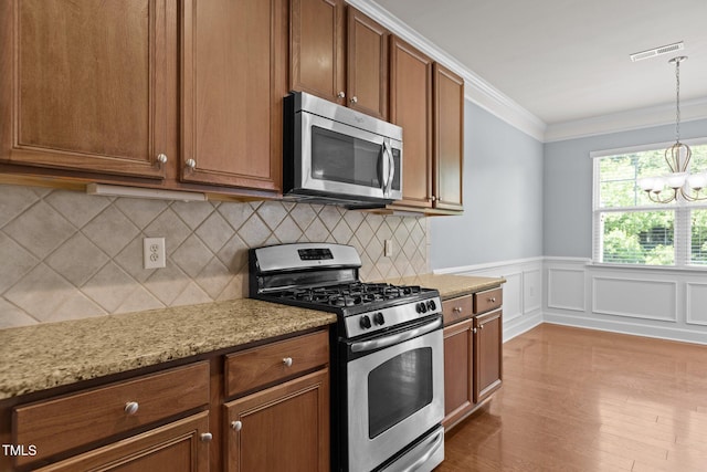 2082 Weston Green Loop, Cary, NC 27513 - kitchen featuring stainless steel appliances, a chandelier, dark wood-style floors, brown cabinetry, and light stone countertops