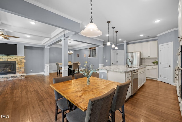 1896 Blue Jay Pt, Apex, NC 27502 - dining room with crown molding, ceiling fan, ornate columns, dark wood-style flooring, and a stone fireplace