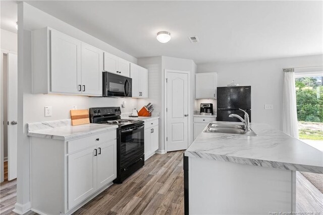 905 Sapphire Stone Ln, Hope Mills, NC 28348 - kitchen featuring black appliances, a sink, light wood finished floors, and white cabinetry