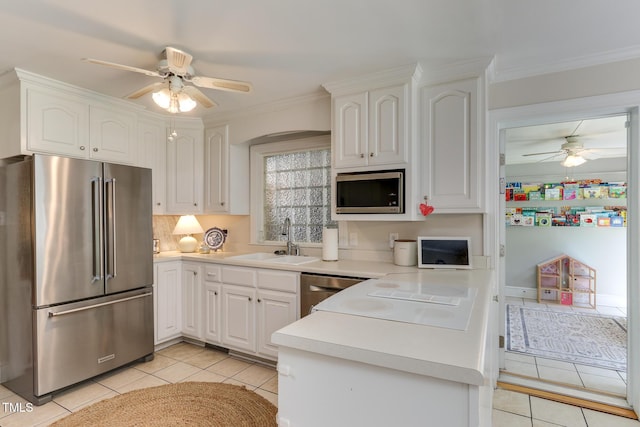 1206 Ivy Ln, Raleigh, NC 27609 - kitchen with stainless steel appliances, ceiling fan, a sink, light tile patterned floors, and ornamental molding