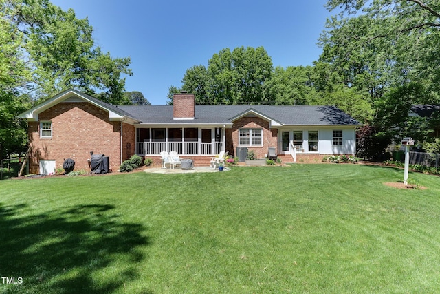 1206 Ivy Ln, Raleigh, NC 27609 - rear view of house featuring brick siding, a sunroom, a chimney, and a yard