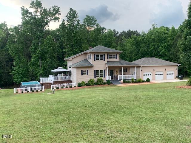 49412 River Run Rd, Albemarle, NC 28001 - view of front facade with a porch, a front yard, a garage, a forest view, and a chimney